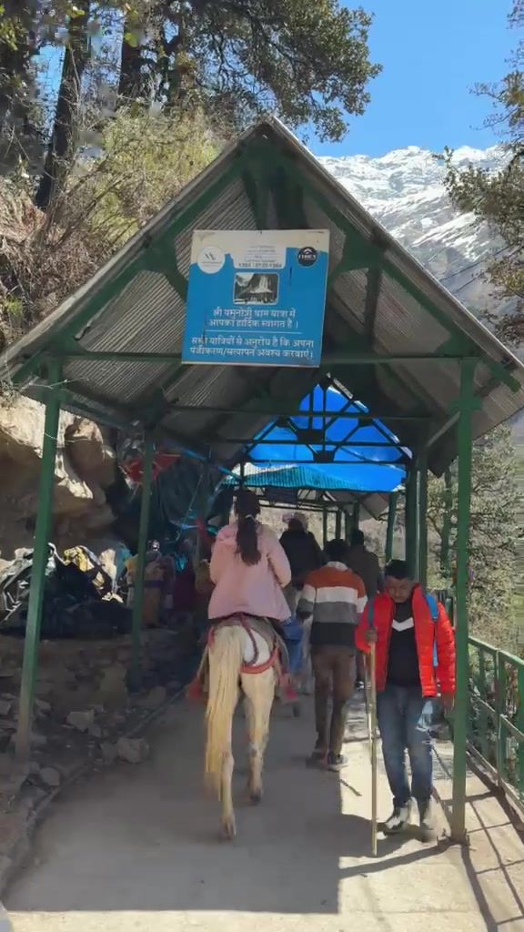 Walkers and a pony rider pass under a covered, green-roofed section of the trek.